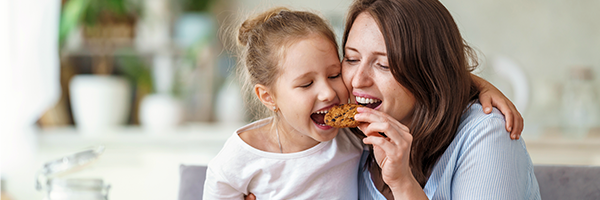 Madre e hija comiendo felices una galleta